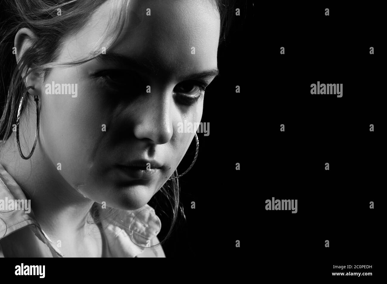 donna triste piangendo, guardando la fotocamera su sfondo nero, ritratto closeup, monocromatico Foto Stock