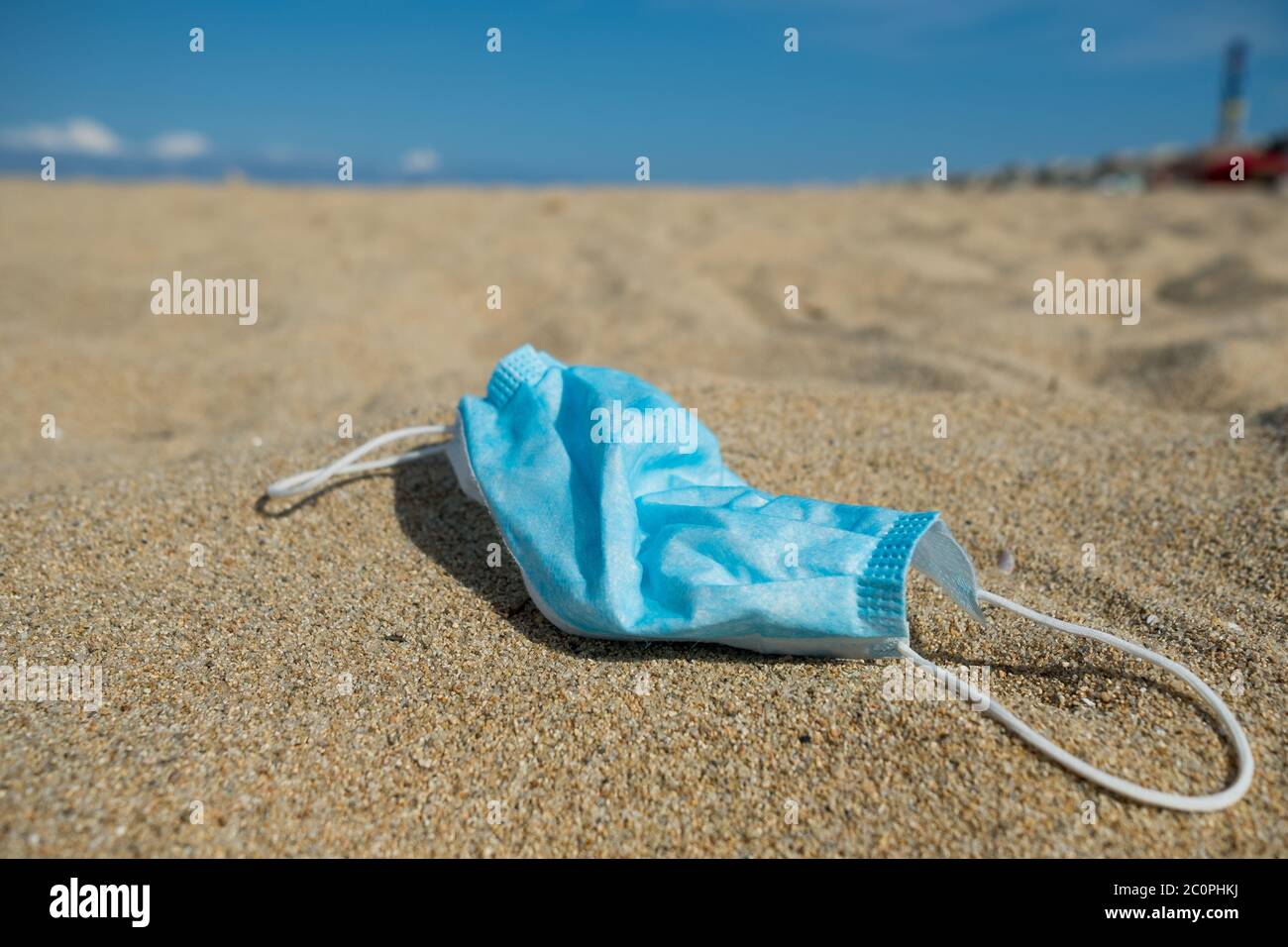 primo piano di abbandonata maschera monouso come rifiuti sulla spiaggia, utilizzato per la protezione contro il virus corona e ora una minaccia per l'ambiente Foto Stock