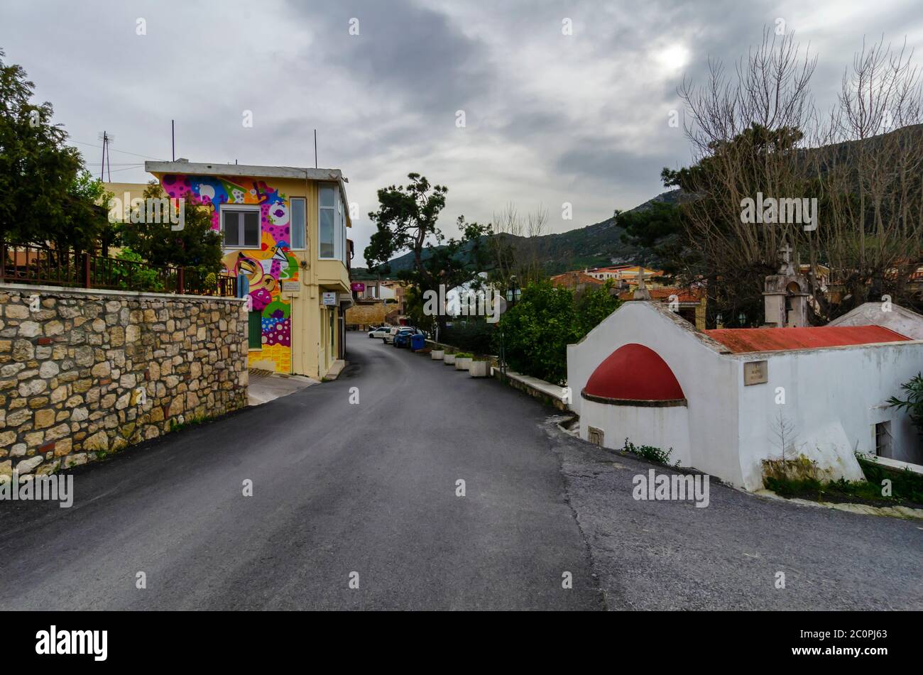 Archanes, Creta / Grecia. Vista sulla strada della città di Archanes. La vecchia cappella di santa Caterina sulla destra. La montagna Juktas sullo sfondo Foto Stock