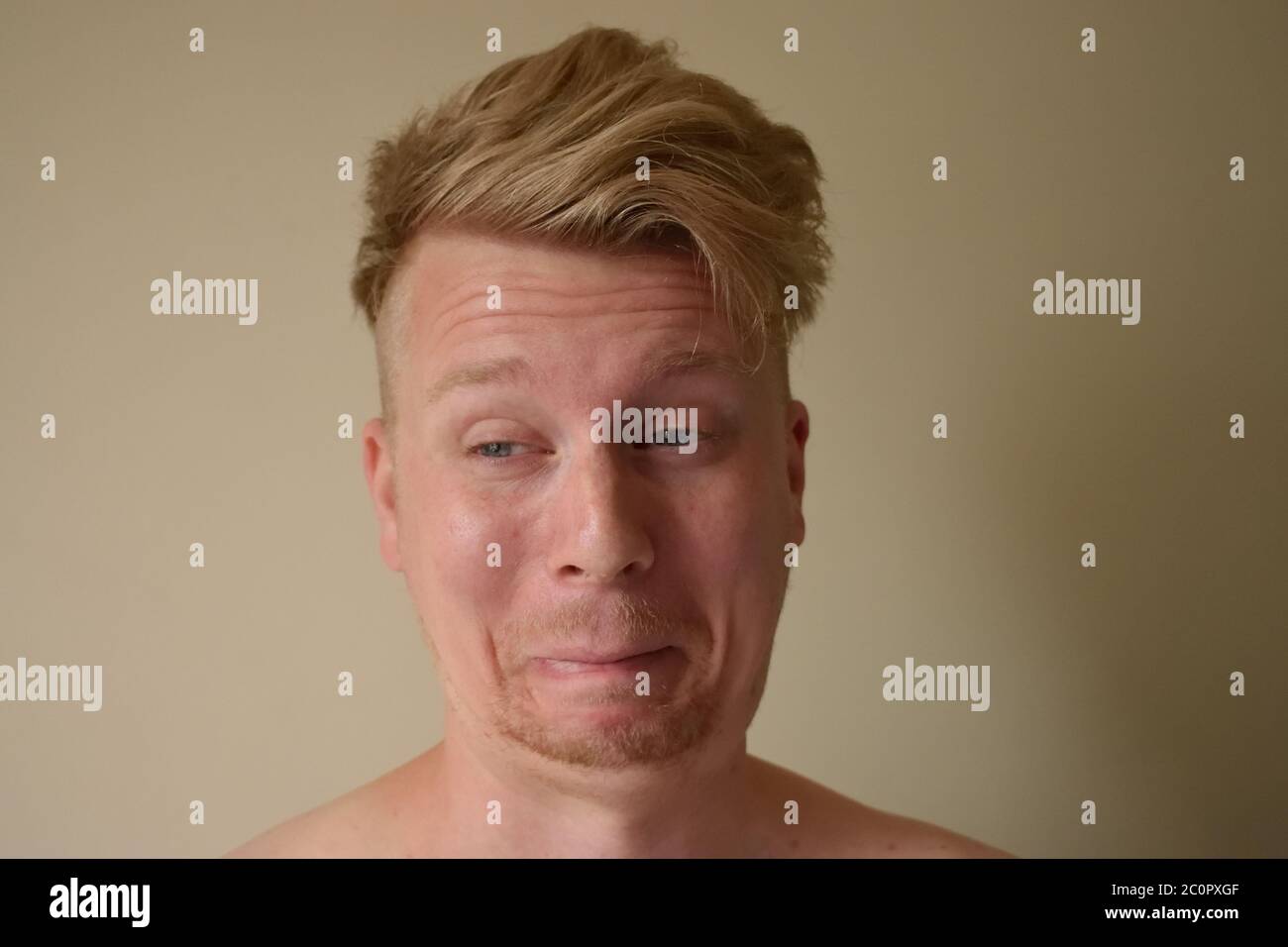Giovane uomo che tira un volto divertente cercando di non ridere Foto Stock