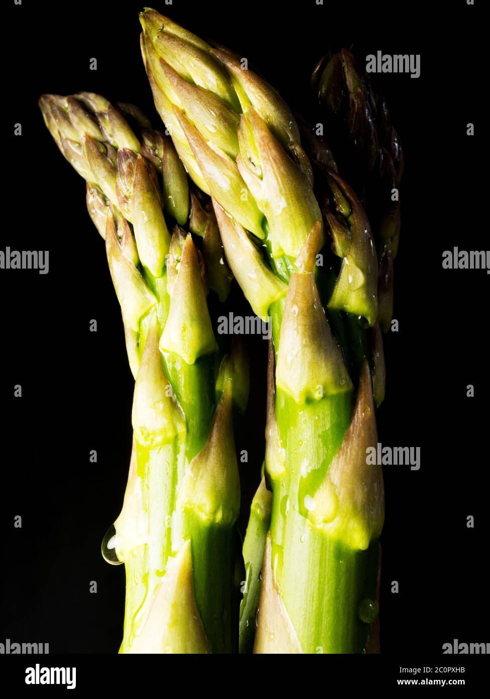 Tre spighe di asparagi freschi su fondo nero Foto Stock