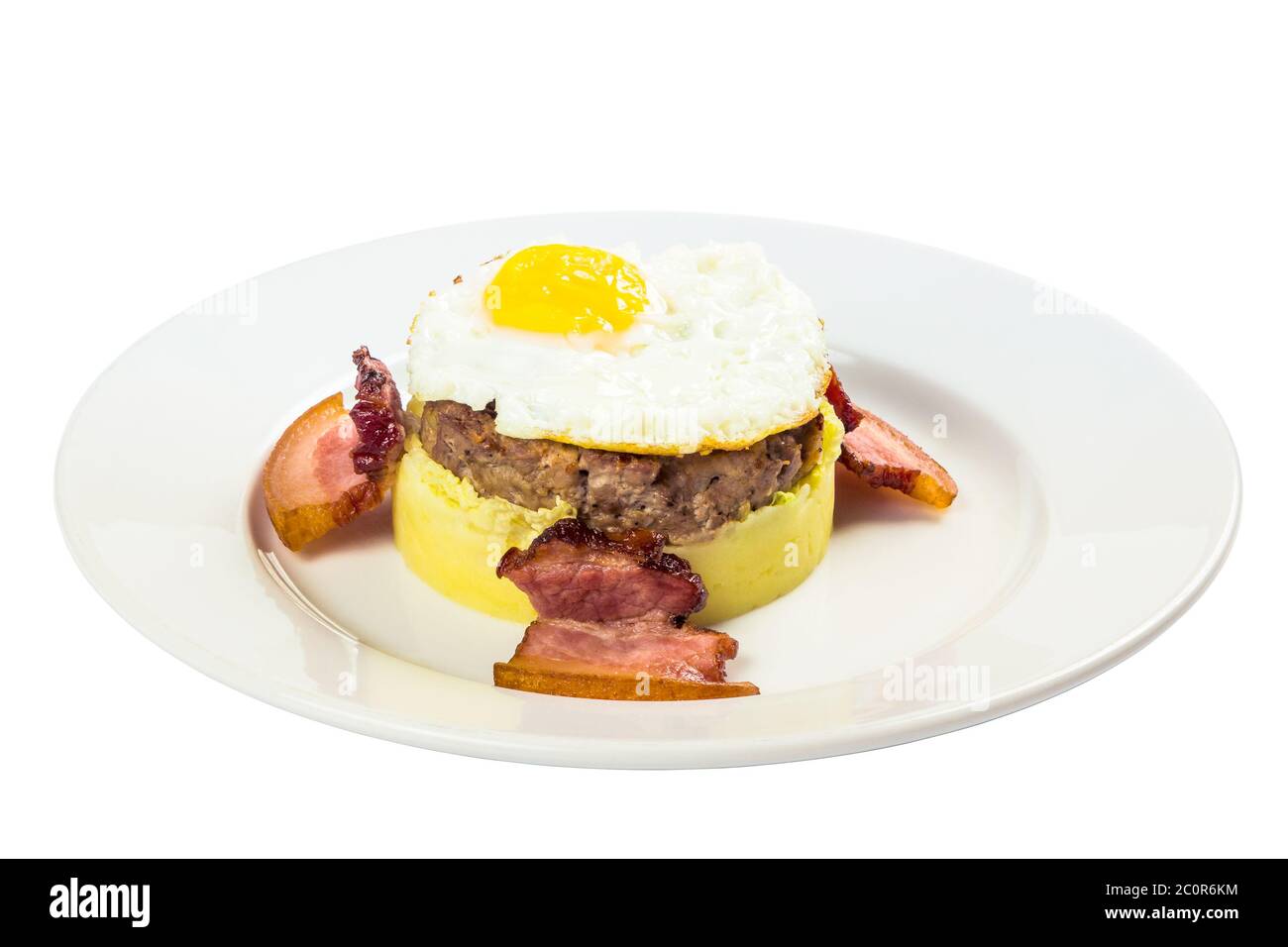 colazione a base di omme. uova fritte e polpettine di carne sulla patata fritta, decorata con pancetta. cibo isolato su sfondo bianco. vista laterale Foto Stock