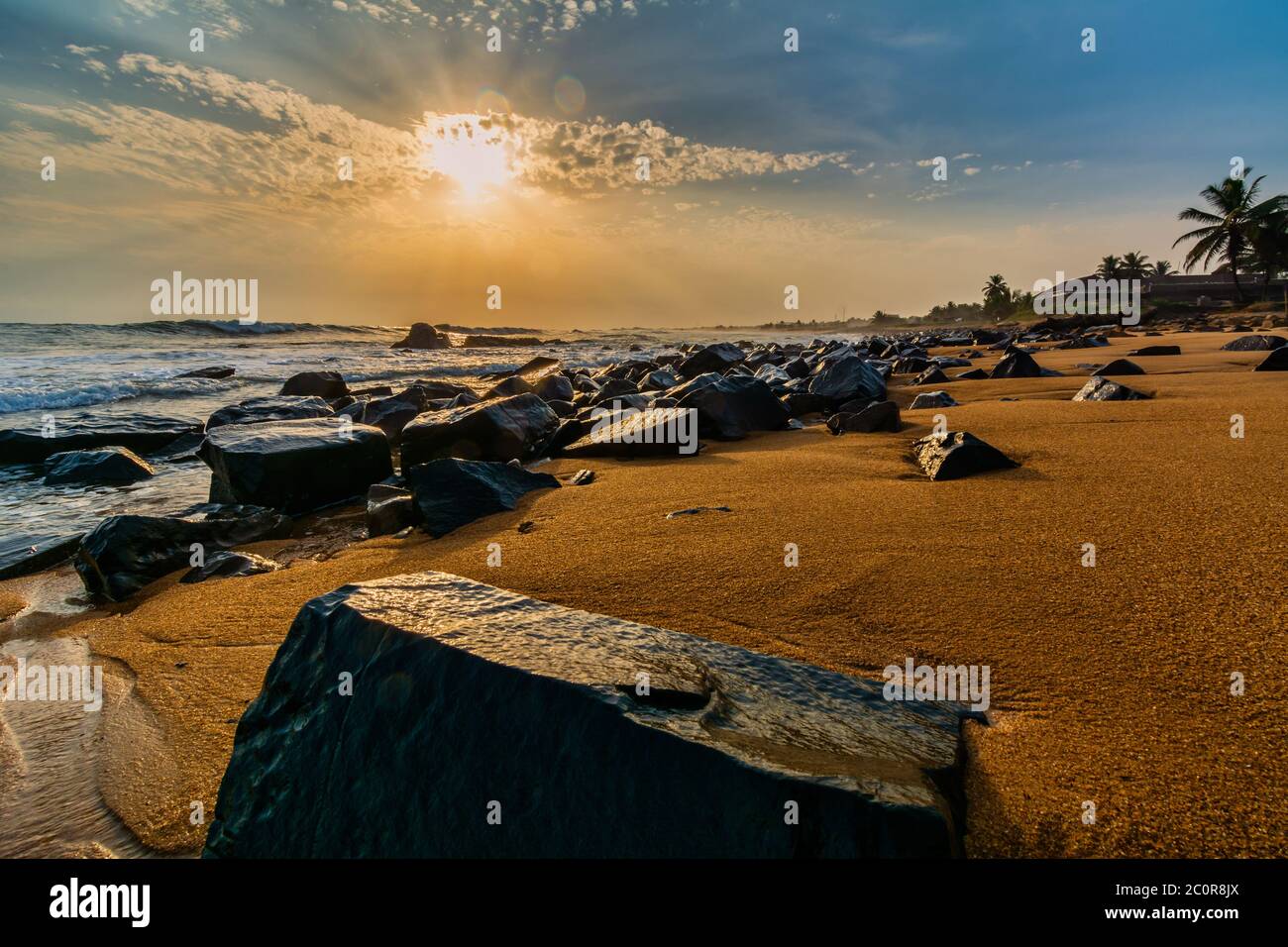 Spiaggia con sabbia rossa e rocce nere con un bellissimo tramonto a Congo Town, Monrovia, Liberia Foto Stock