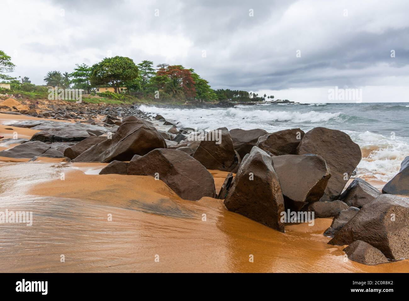 Spiaggia con sabbia rossa e rocce rosse con un cielo suggestivo a Città del Congo, Monrovia, Liberia Foto Stock
