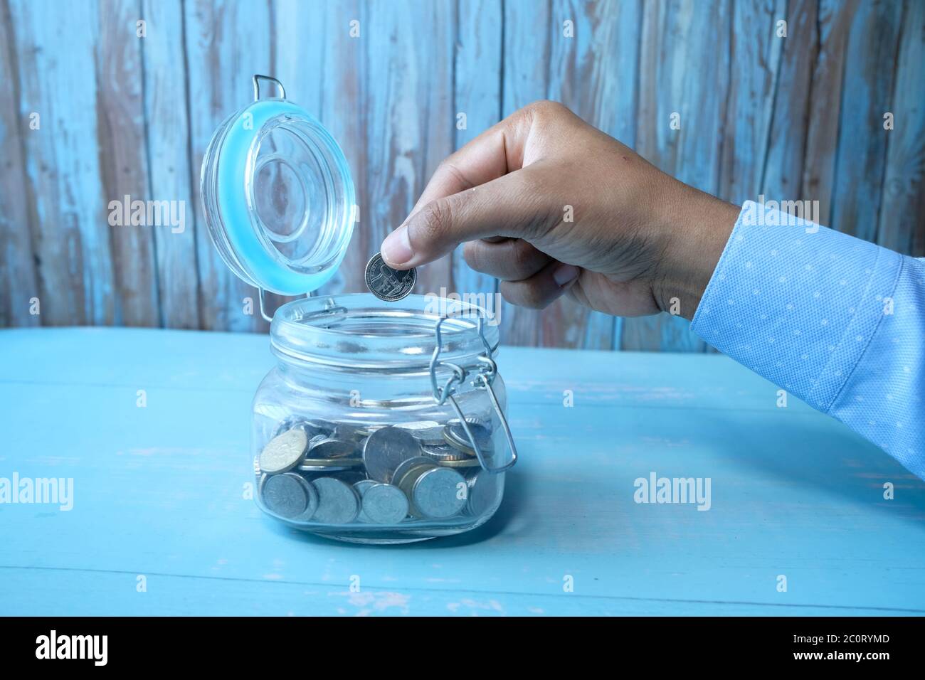 Primo piano di monete uomo risparmio in un vaso Foto Stock