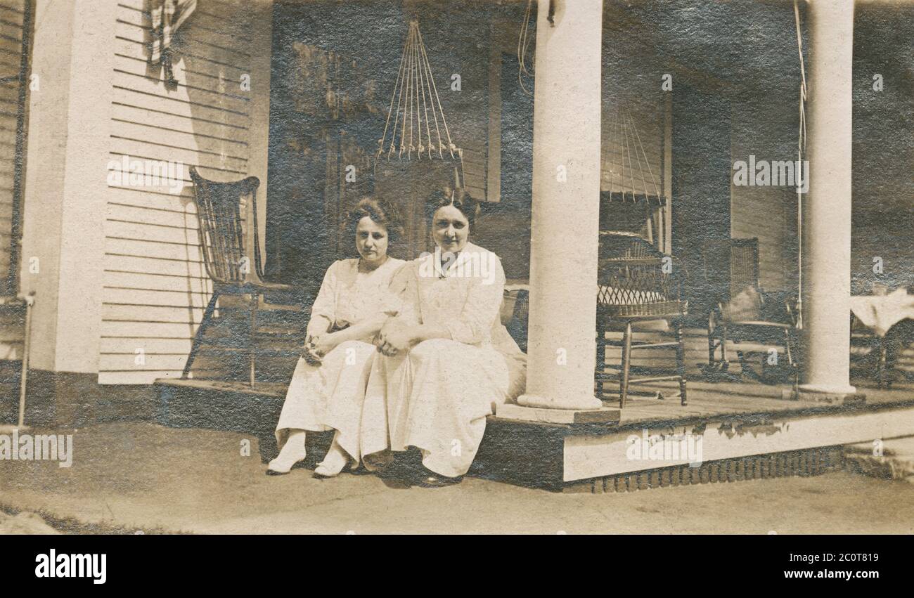 Antica fotografia del 1913 aprile, due donne sedute sul portico esterno. Posizione esatta sconosciuta, probabilmente New Hampshire o Massachusetts. FONTE: FOTOGRAFIA ORIGINALE Foto Stock