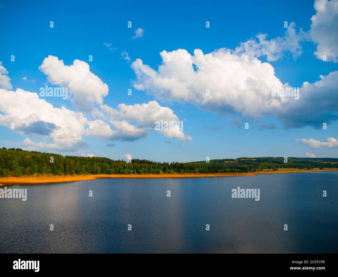 Paesaggio estivo con verdi foreste, cielo blu e nuvole bianche riflesse nel lago. Foto Stock