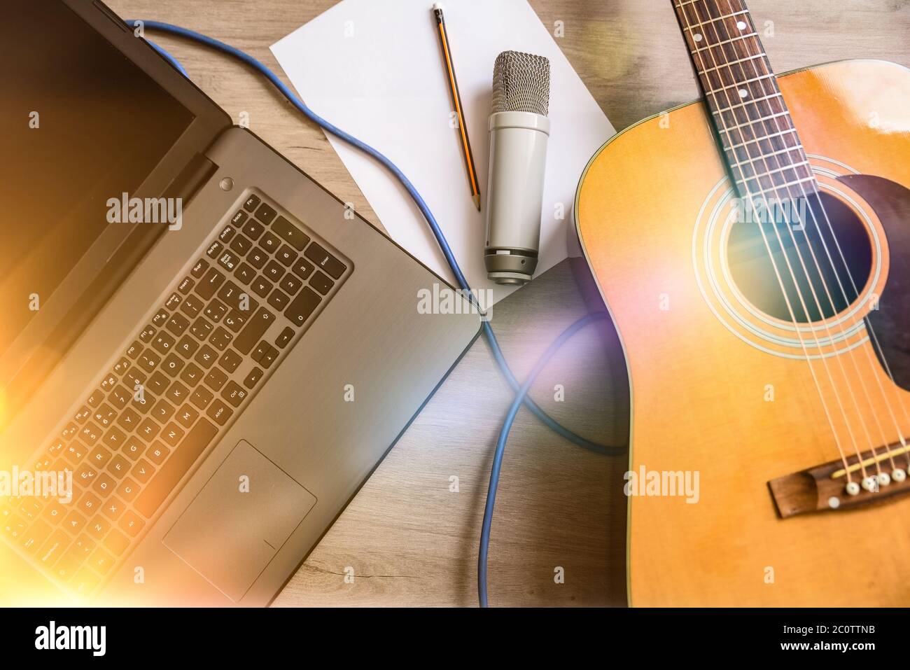 Apparecchi di registrazione per la musica con chitarra acustica, microfono e laptop su tavolo di legno. Vista dall'alto Foto Stock