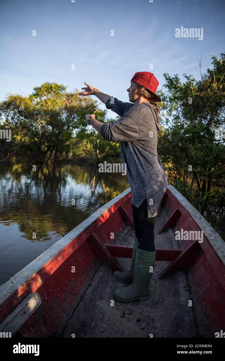 donna bionda che pesca su una canoa nel fiume Foto Stock