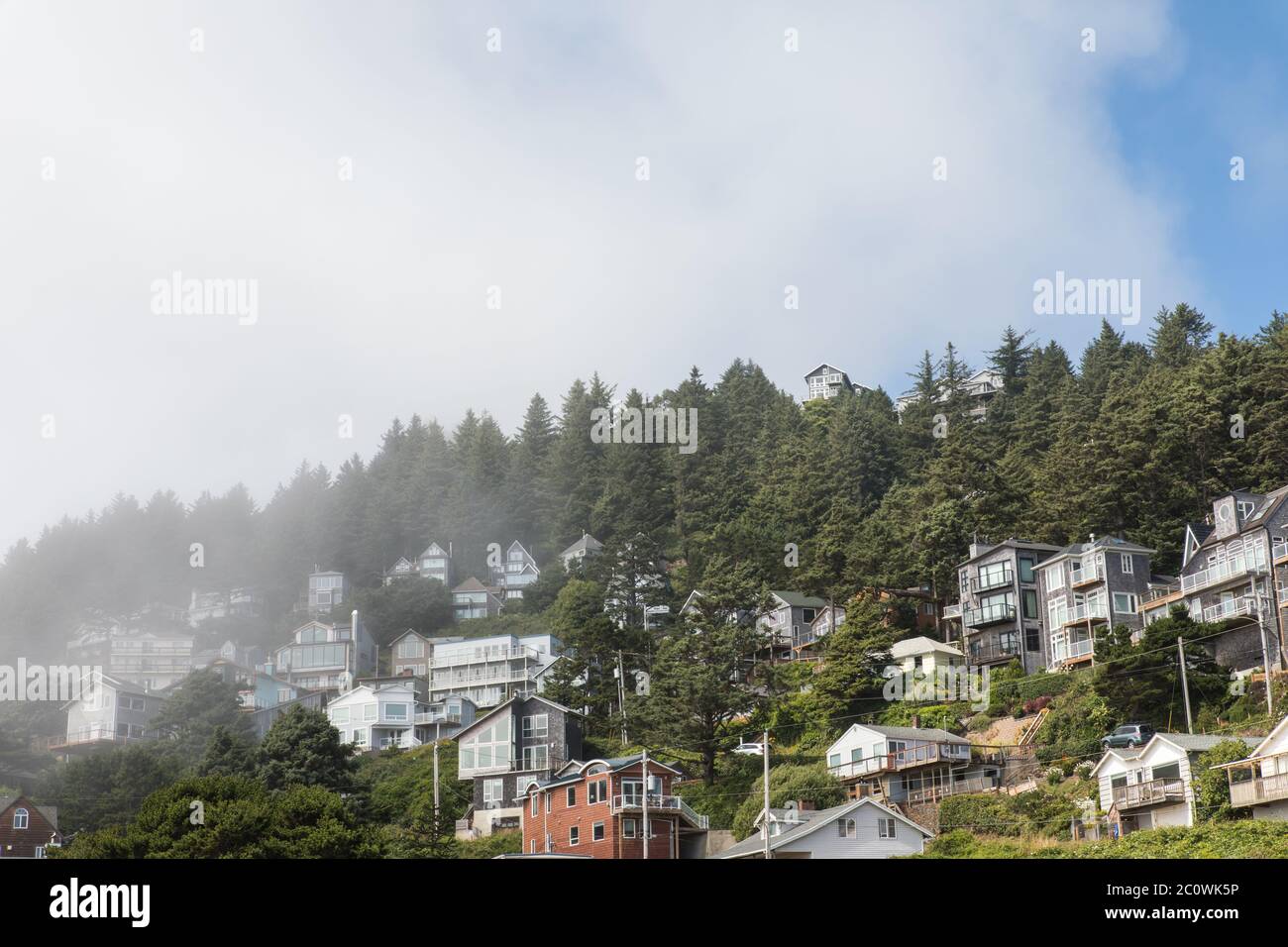 Nebbia che arriva a riva sulle case di collina in Oceanside Oregon Foto Stock