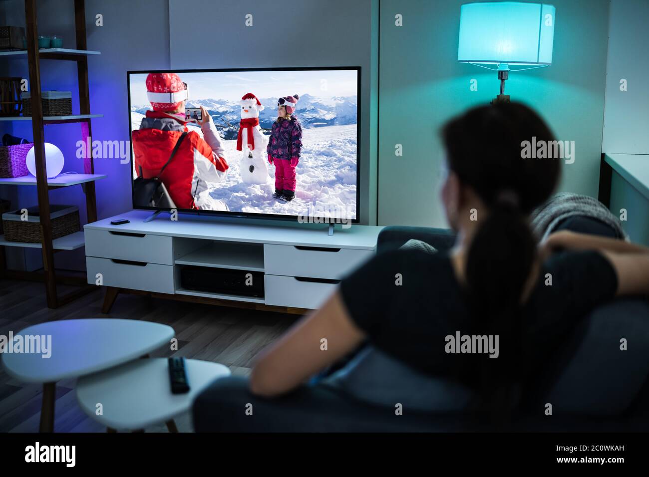 Donna che guarda la TV sul divano o sul divano. Guarda la televisione Foto Stock