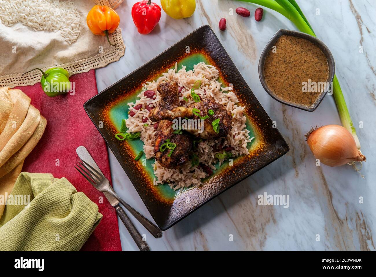 Autentica zampa di pollo piccante giamaicano a jerk con peperoncini scotch con coperchio serviti con riso al cocco e piselli Foto Stock