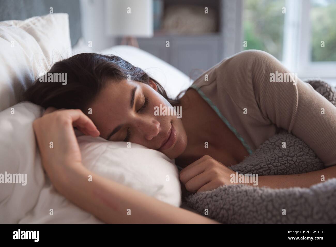 Donna di razza mista che si trova a letto durante il coronavirus covid19 pandemia Foto Stock