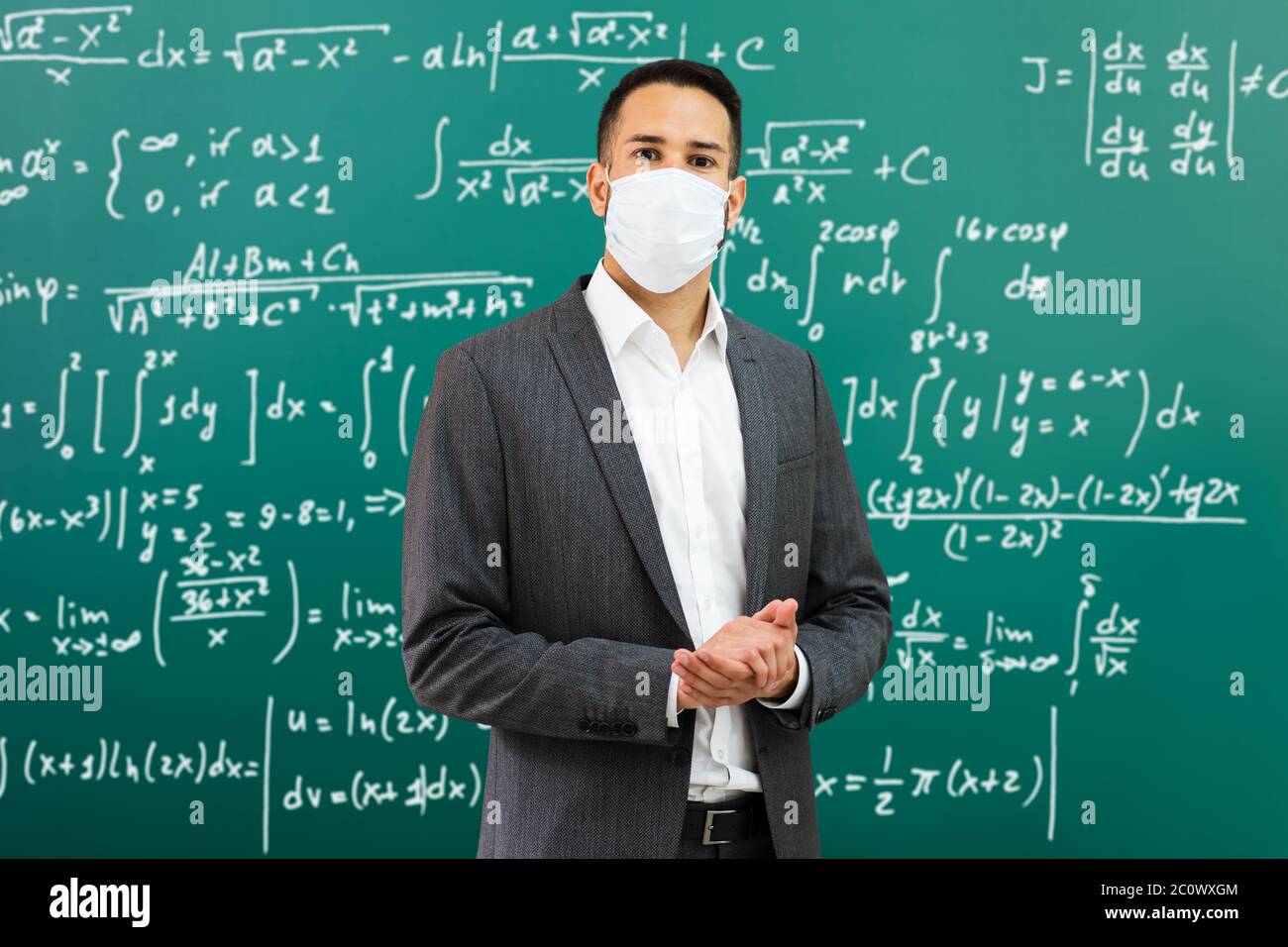 Professore universitario in piedi in classe indossando maschera facciale Foto Stock