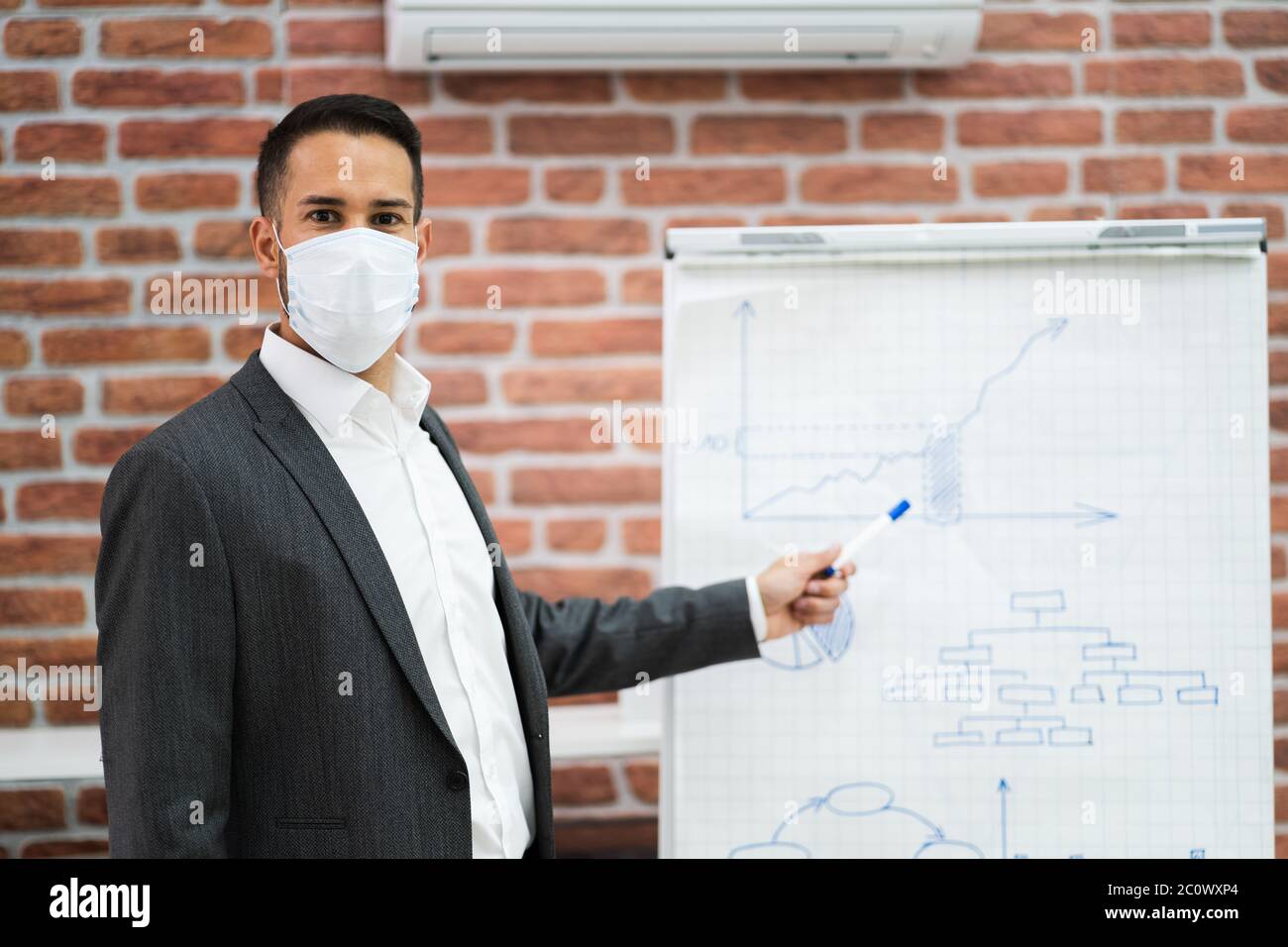 Uomo di affari che dà la presentazione di addestramento in ufficio in maschera di faccia Foto Stock