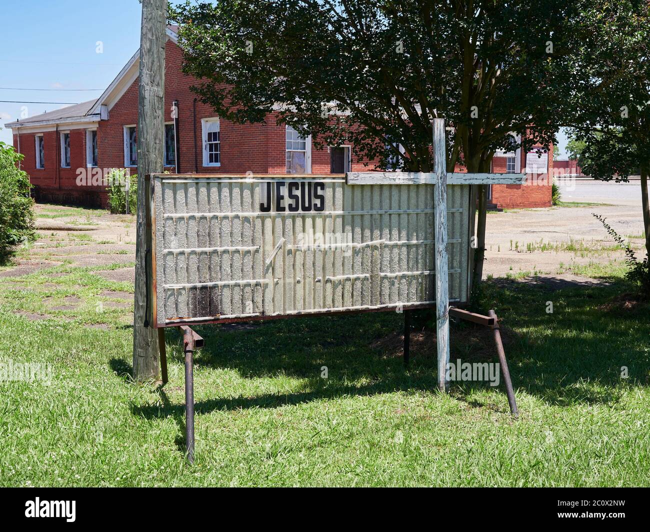 Vecchio, vecchio e faticoso segno della chiesa con il nome Jesus visualizzato in piedi accanto ad una croce bianca con pittura peeling in Montgomery Alabama USA. Foto Stock