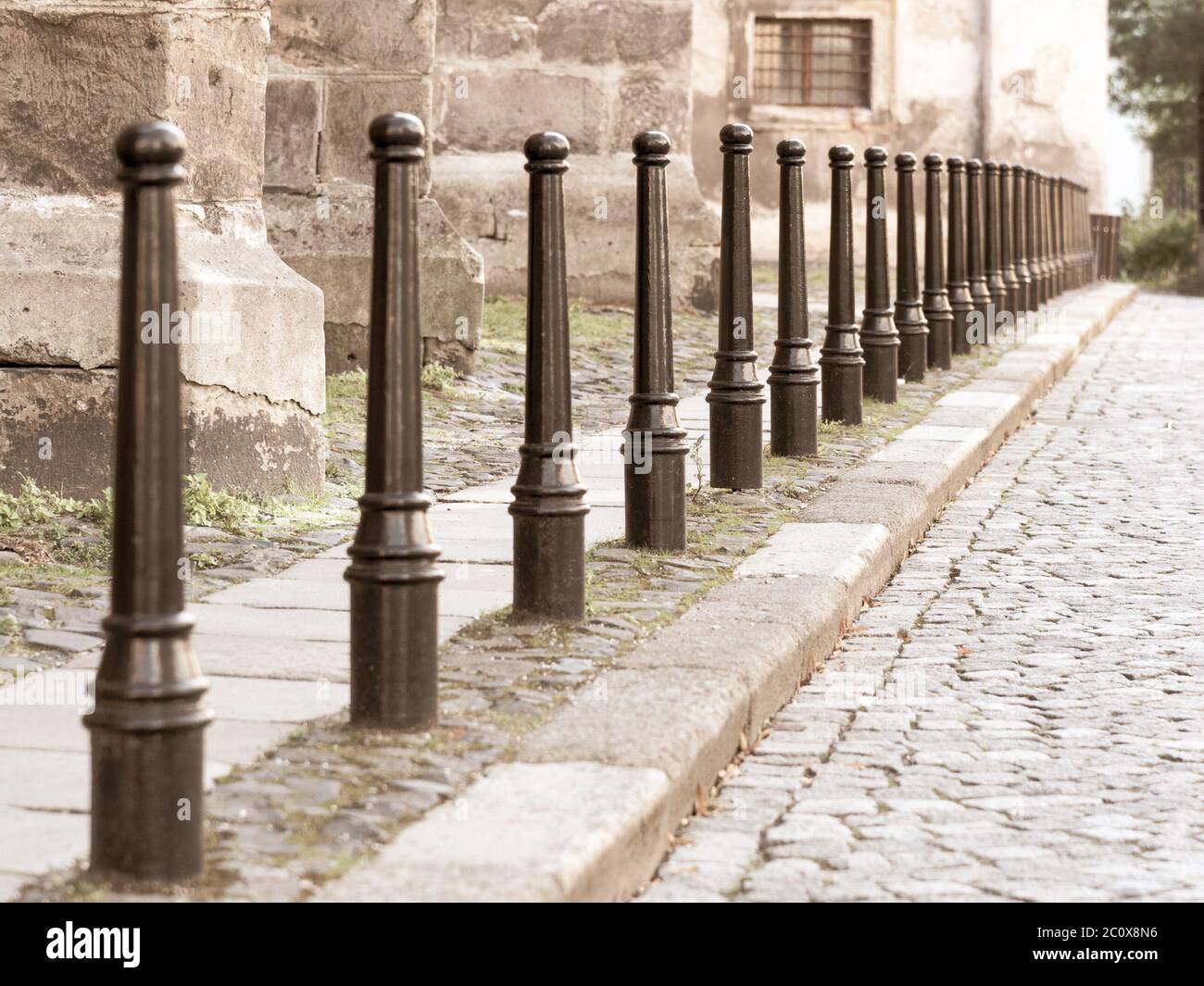 Fila di colonne di ferro tra strada acciottolata e marciapiedi pedonali. Foto Stock