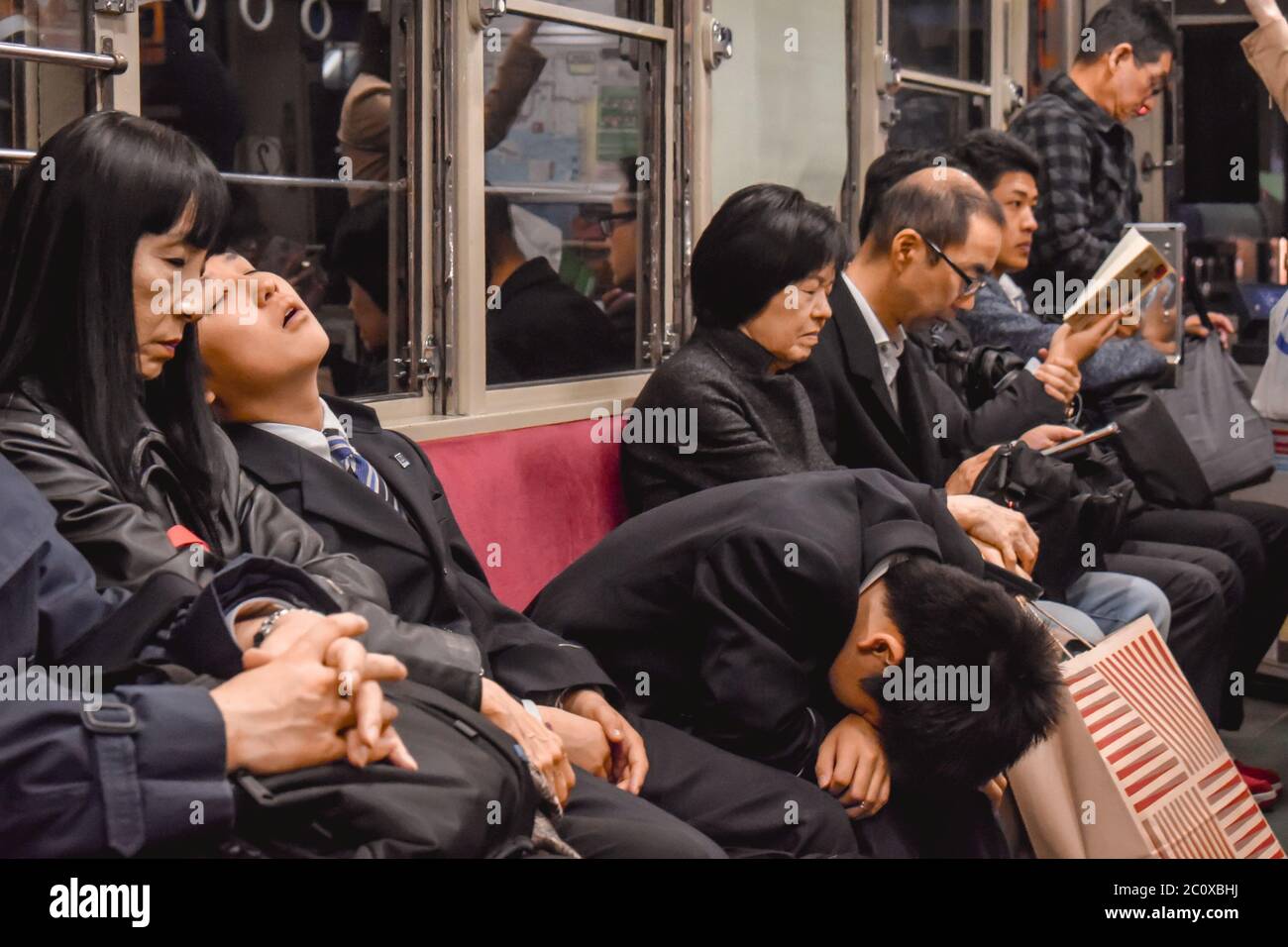 Passeggeri che dormono su un treno notturno in Hiroshima Giappone Foto Stock