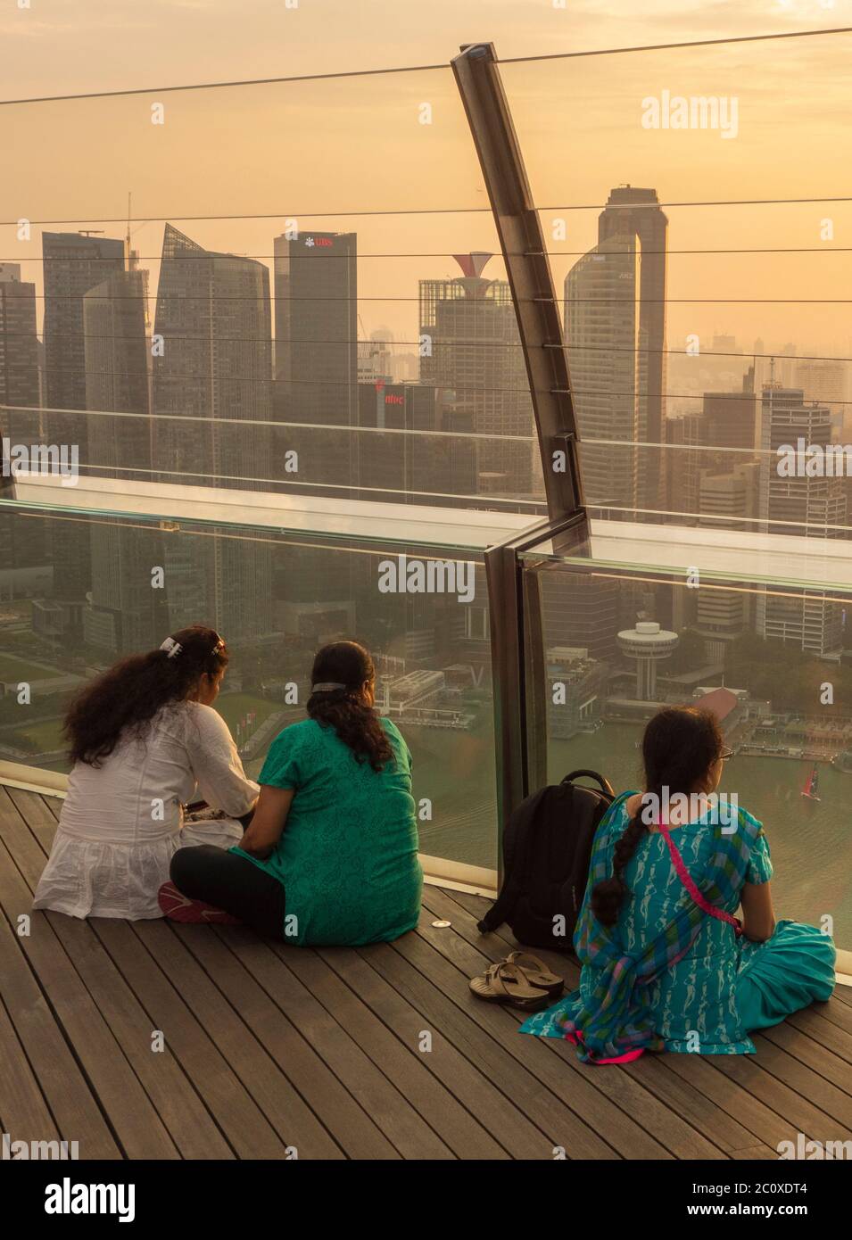 Le donne osservano il tramonto sullo skyline del centro di Singapore, visto dalla terrazza dell'hotel Marina Bay Sands. Singapore Foto Stock