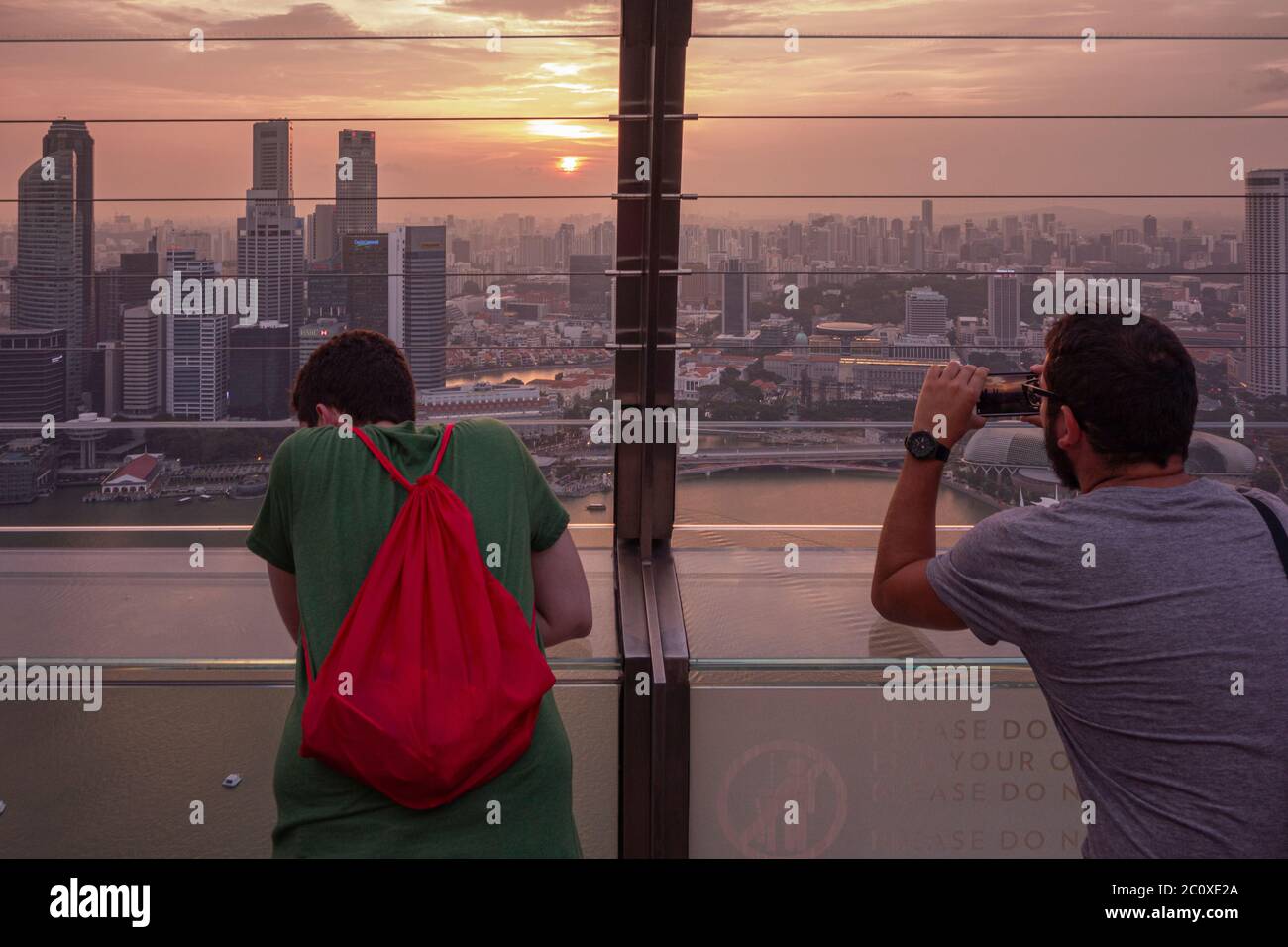 La gente osserva il tramonto sullo skyline del centro di Singapore, visto dalla terrazza dell'hotel Marina Bay Sands. Singapore Foto Stock
