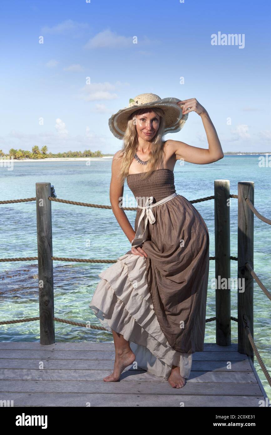 bella donna in un abito lungo su una piattaforma di legno sul mare Foto Stock