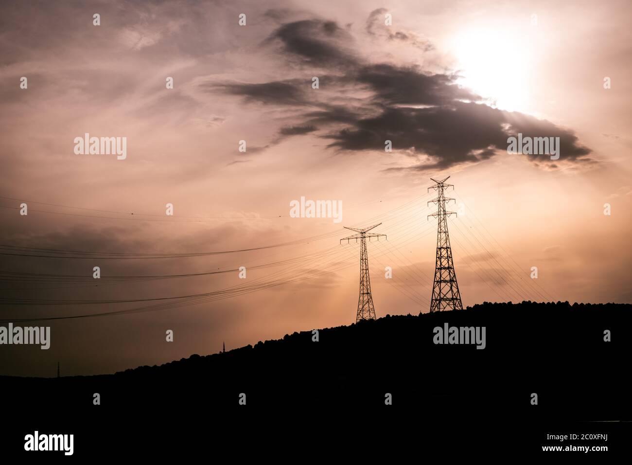 le principali linee elettriche della città, le enormi torri in metallo sulla collina. atmosfera suggestiva con il cielo e le nuvole color tramonto. grande piano generale. Foto Stock