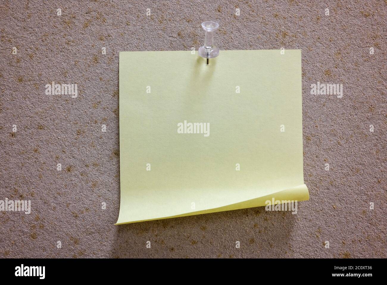 Una nota gialla vuota su una bacheca con un pin Foto Stock