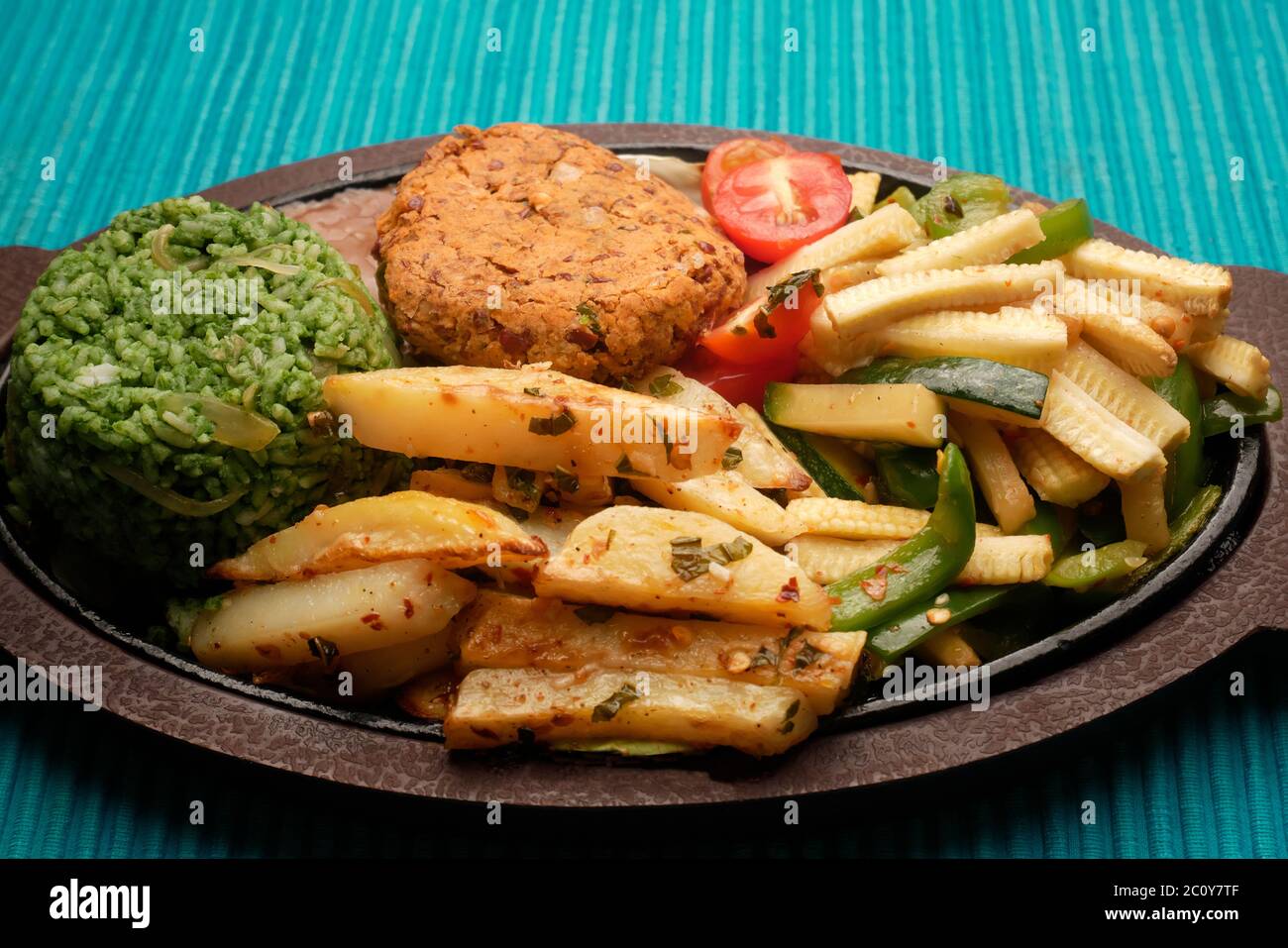 SIZZLER VEGETALE CON PATATINE FRITTE, PATATINE DI FAGIOLI, RISO SPINACI, ZUCINI, CAPSICUM, POMODORI CILIEGINI, CAVOLO, CIPOLLE E SALSA DI FAGIOLI NERI Foto Stock