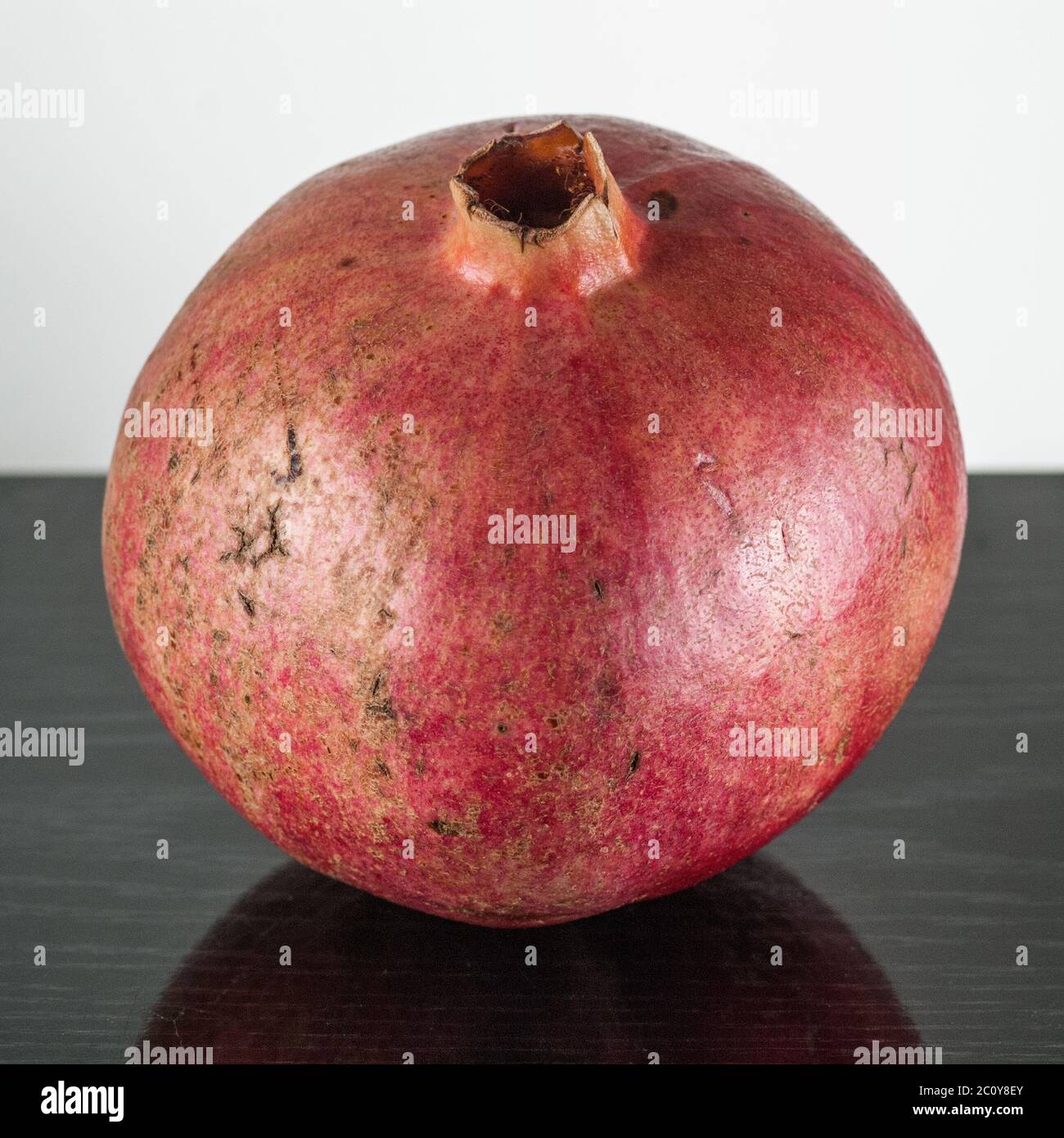 Semi maturi frutti di melograno isolato su nero piano in legno e sfondo bianco Foto Stock