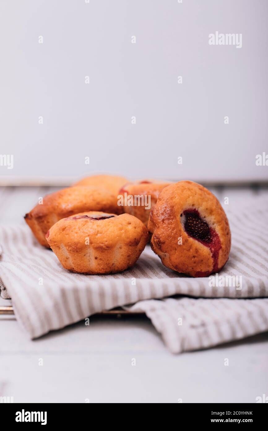 Muffin fatti in casa alle fragole su vassoio di legno con tovagliolo bianco controllato poco pulito. Foto Stock