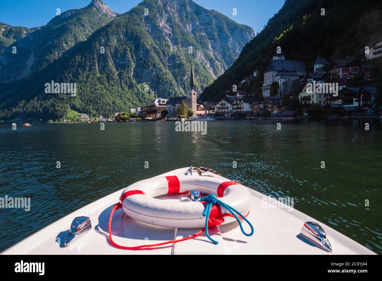 In barca sul lago Hallstatt con un motoscafo elettrico che guarda la città di Hallstatt con la guglia della Chiesa evangelica Foto Stock