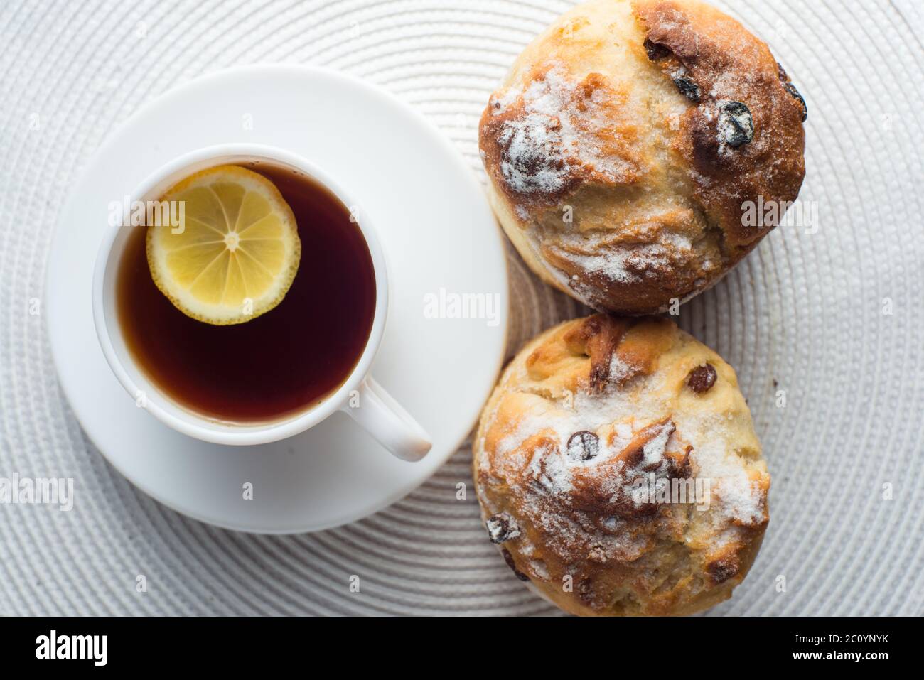 Due fatti in casa muffin alla carota con tappo di tè e limone sul tessuto bianco sfondo. vista superiore Foto Stock