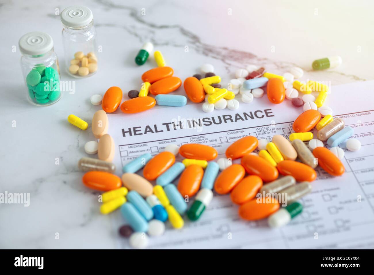 Primo piano di pillole di medicina colorata sulla fattura di carta di assicurazione. Concetto di assistenza sanitaria Foto Stock