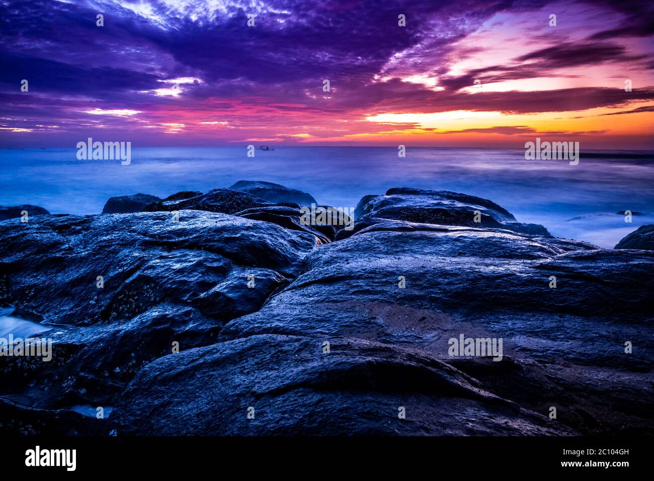Bellissima alba sulla spiaggia a lunga esposizione. Elementi in movimento alba e foto onda dalla spiaggia rocciosa in india. Cielo rosso nella baia di benga Foto Stock