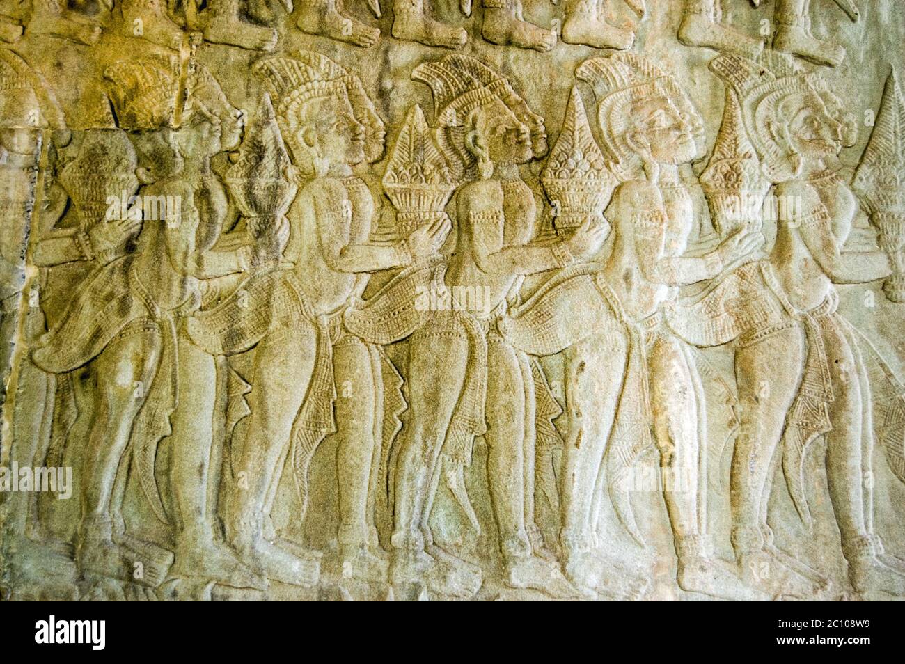 Bassorilievo scultura di una processione di dei che portano doni per Vishnu su un muro nell'angolo nord-ovest del tempio di Angkor Wat che mostra scene della Ra Foto Stock