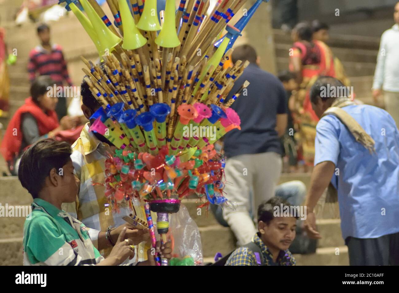 Indiano piccolo commerciante che vende i giocattoli tradizionali del flauto & dei bambini del bambù a Varanasi, India. Foto Stock