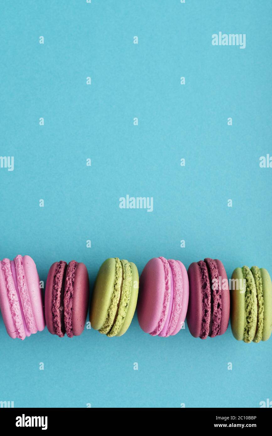 Fila di colorati macaron francesi su sfondo blu. Vista dall'alto. Colori pastello Foto Stock