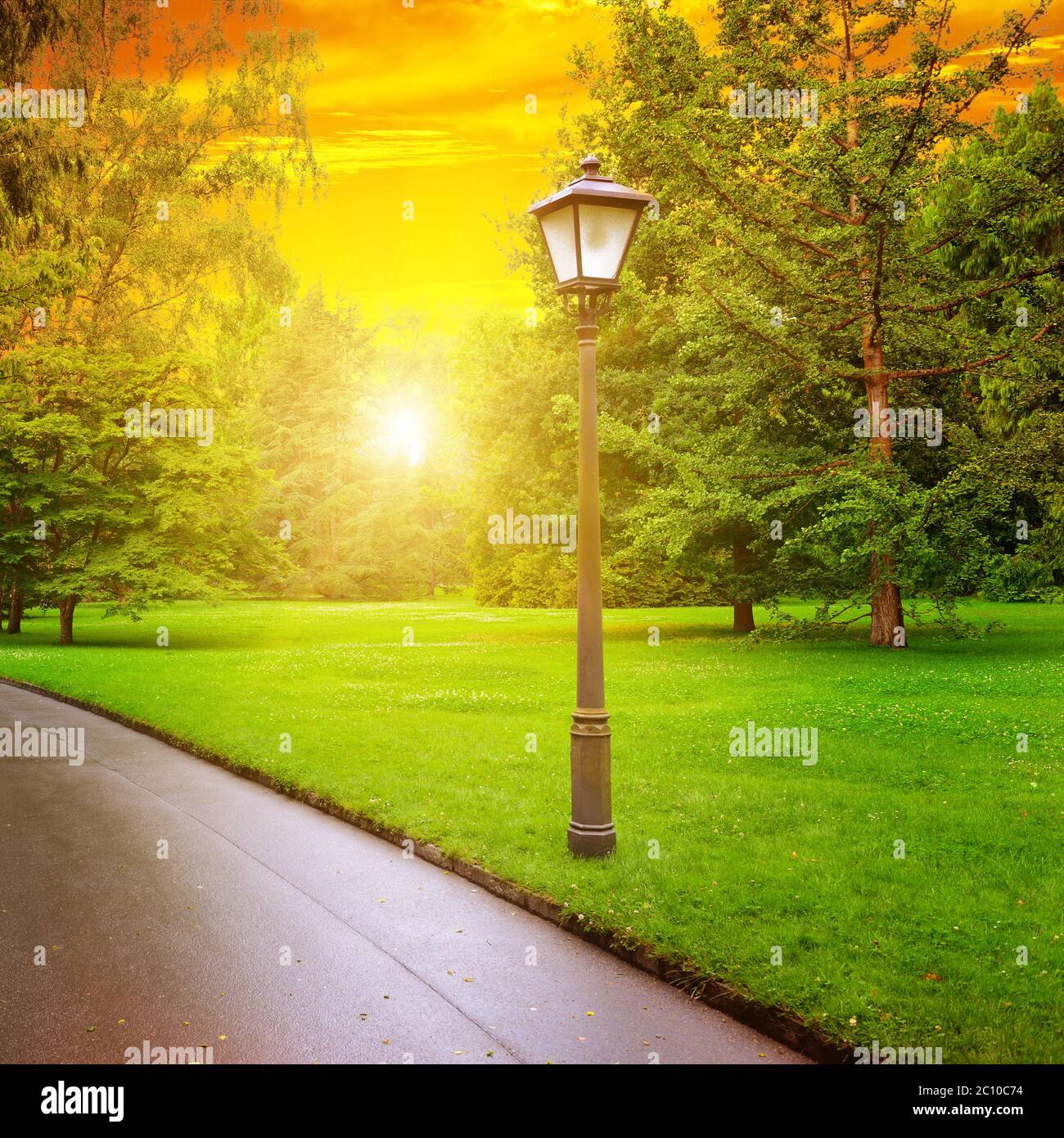 Scenografico alba nel parco con passerella pedonale e lanterna Foto Stock