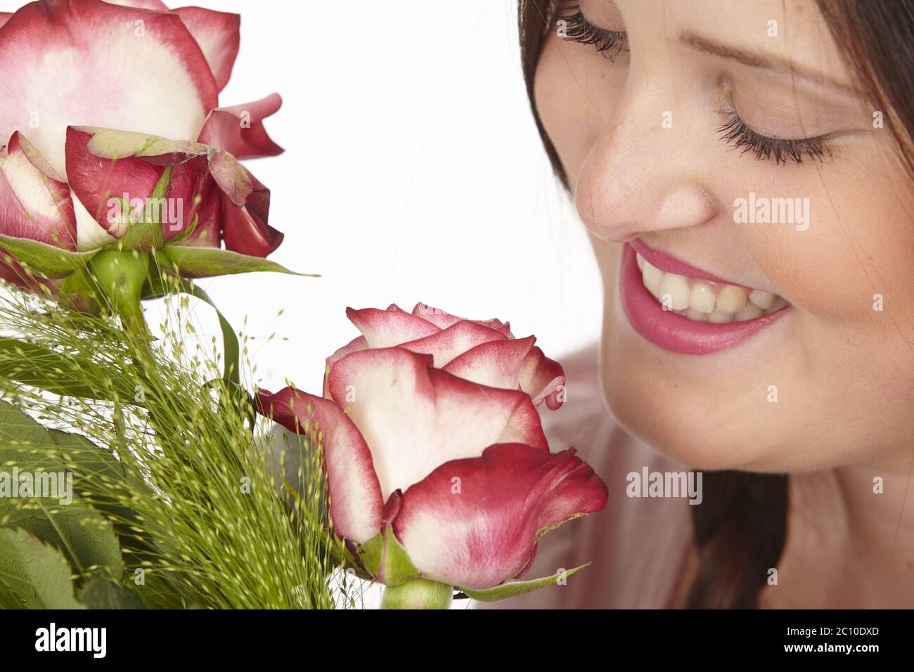 Primo piano di una giovane donna con un mazzo di fiori (rose) Foto Stock