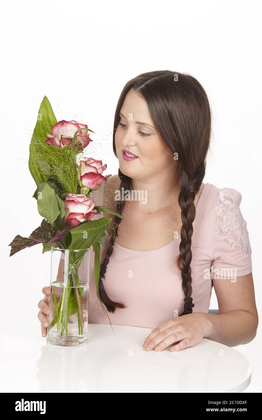 Giovane donna brunetta con trecce e bouquet di fiori al tavolo da bar Foto Stock