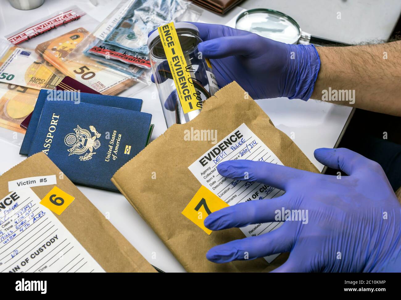 Esperto funzionario di polizia esaminando passaporto americano di una busta di prova nel laboratorio di criminologia, immagine concettuale Foto Stock