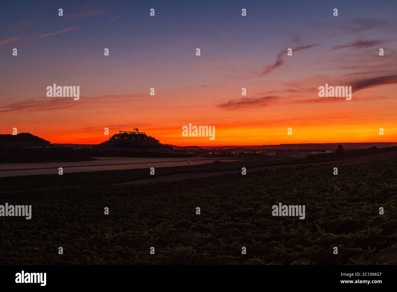 Vista panoramica dei vigneti e dei campi coltivati al tramonto sulla Ribera del Duero, nell'altopiano settentrionale della Spagna, con la sagoma del castello di Peñafiel Foto Stock