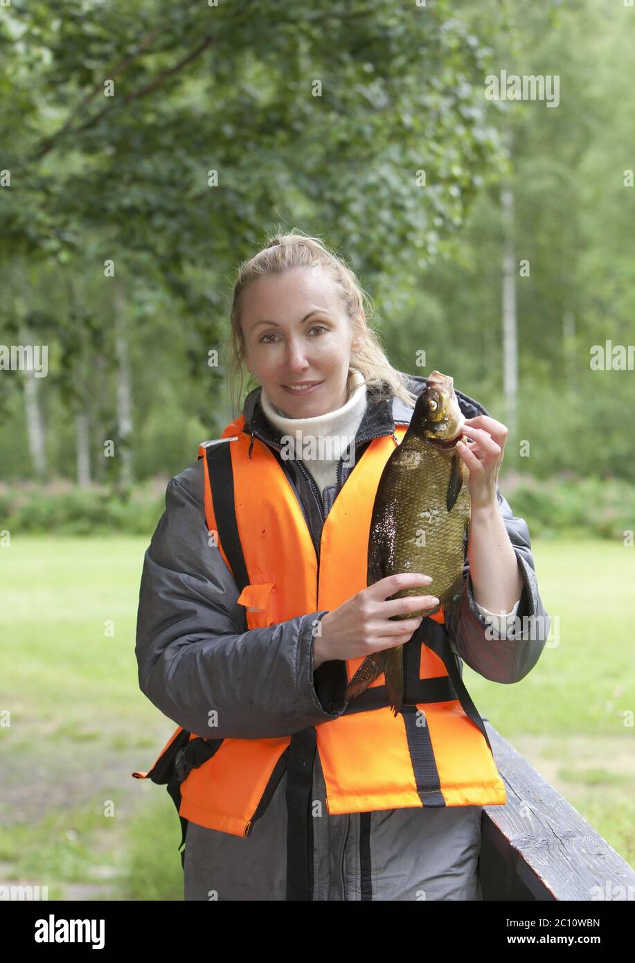 La giovane donna con il pescatore ha catturato l'orata Foto Stock