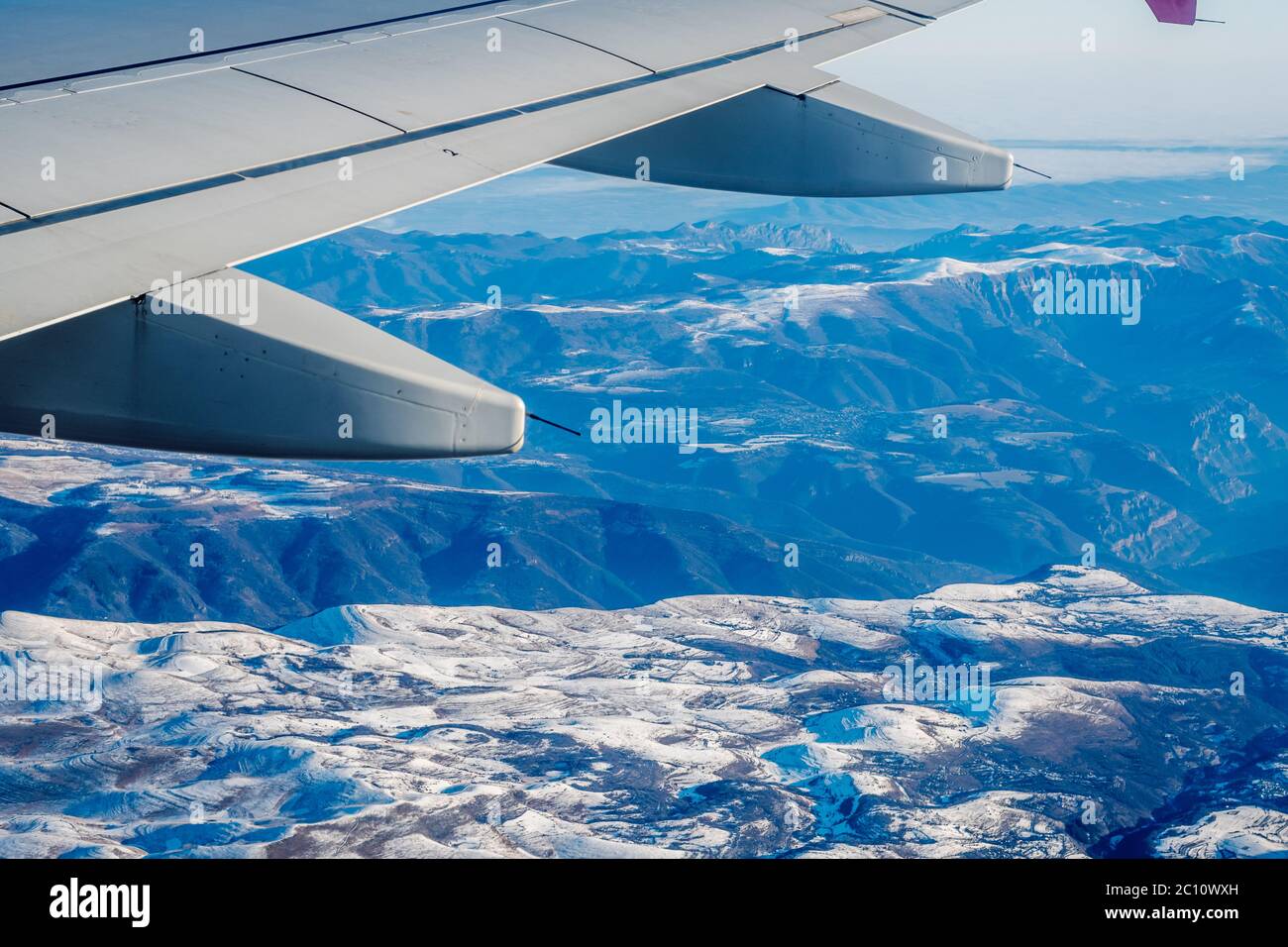 Vista delle imponenti montagne dei Balcani in aereo. Vista panoramica aerea sotto l'ala di un aereo, alte montagne coperte di neve. Foto Stock