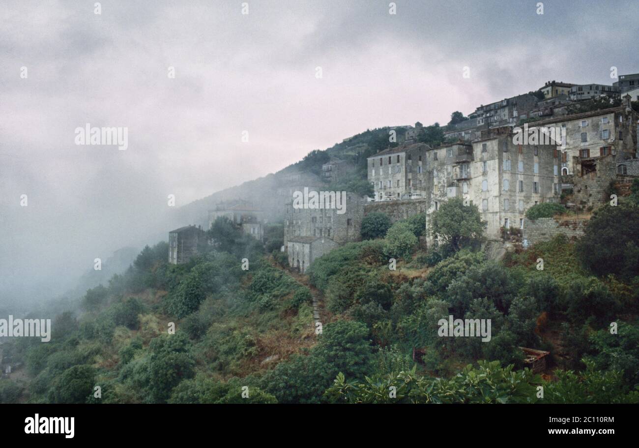 Archivio Corsica. Vecchie case e alberi aggrappati alla collina in una mattina nebbiosa vicino a Sartene. 1980 Foto Stock