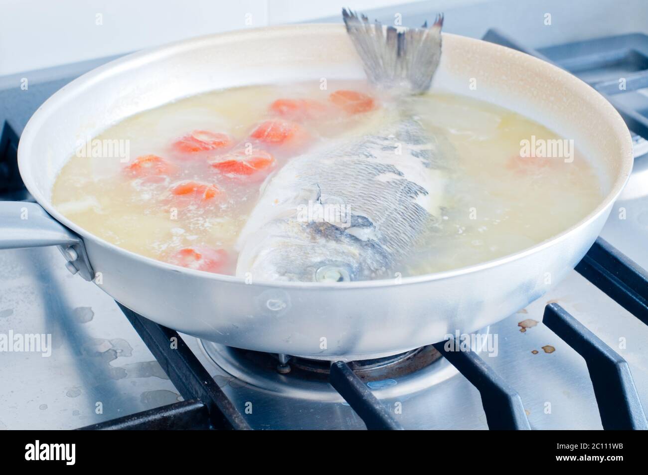 Orate di pesce cotto in acqua pazza, ricetta tipica del sud Italia con acqua di mare, pomodori, cipolle e aglio Foto Stock