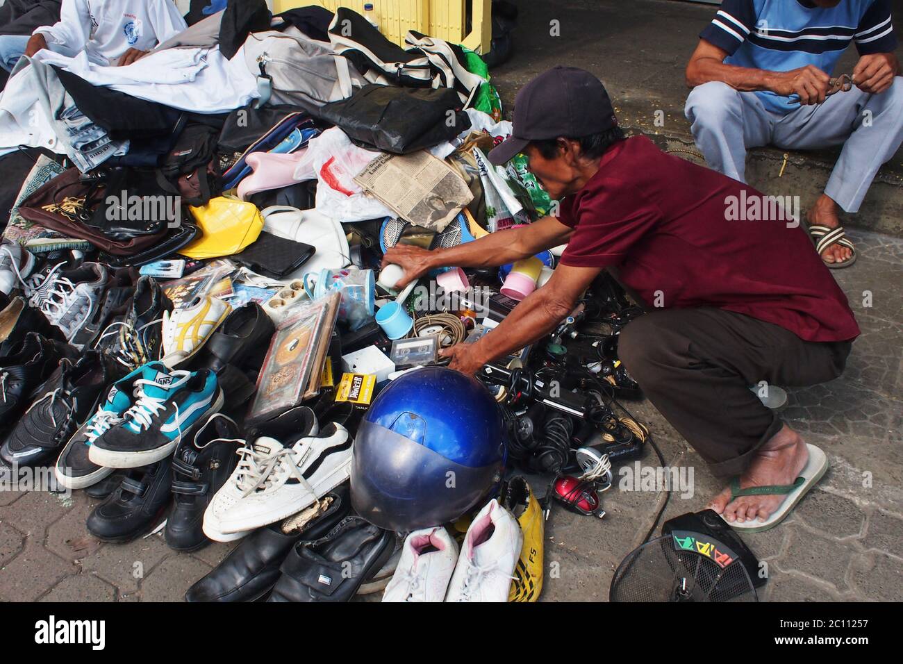 Bogor, West Java, Indonesia - 28 dicembre 2013 : UN potenziale acquirente sembra essere alla ricerca di beni usati venduti sul marciapiede Foto Stock