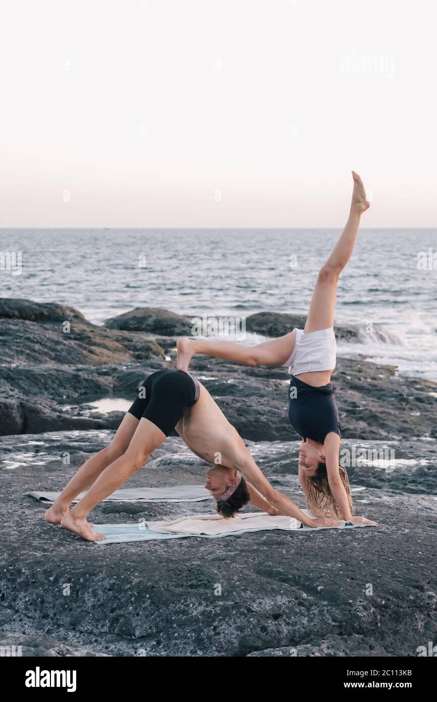 coppia facendo esercizi di yoga all'aperto in spiaggia Foto Stock