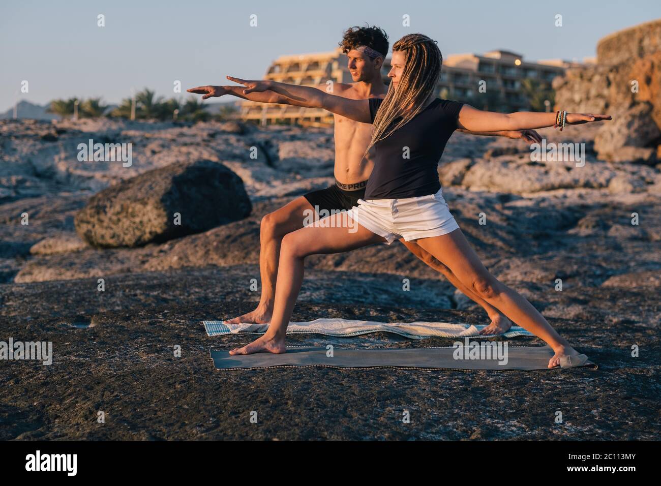 Coppia che pratica yoga all'alba sulla spiaggia di fronte al mare Foto Stock