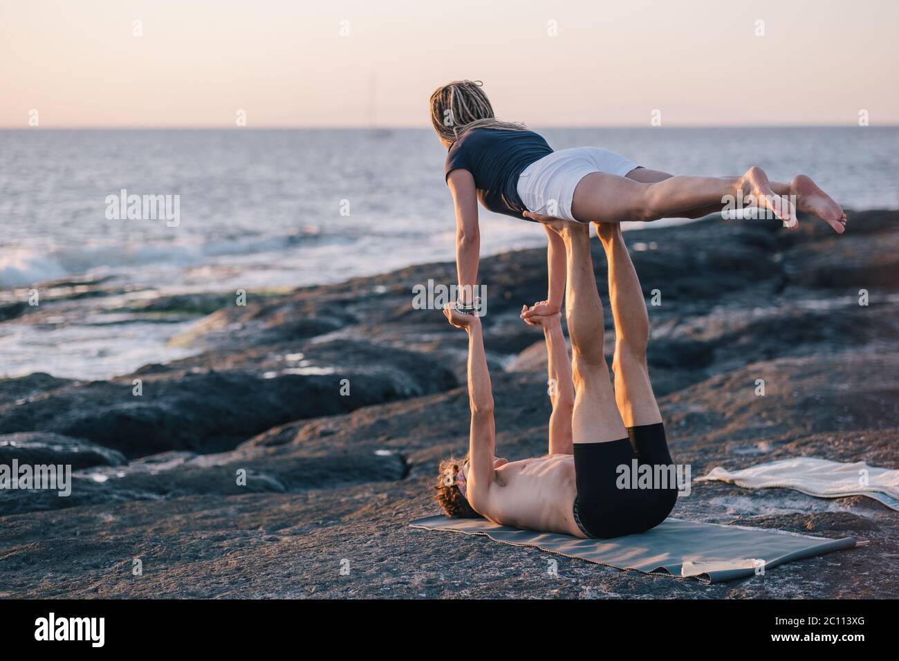 coppia facendo esercizi di yoga all'aperto in spiaggia Foto Stock